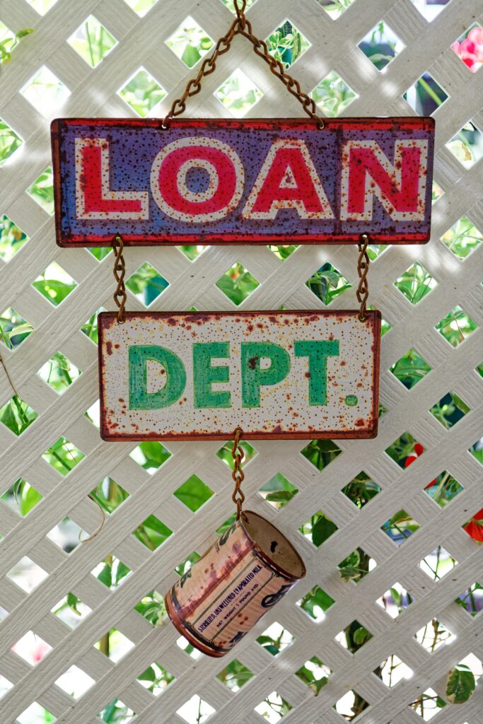A weathered metal signage reading 'Loan Dept.' with a rusty tin can hangs against a lattice.