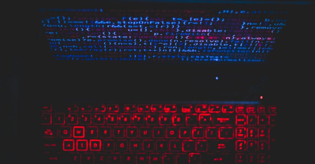Dark-themed laptop setup with a red glowing keyboard and code on screen, ideal for tech enthusiasts.