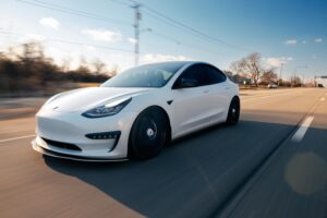 White electric car speeding down a Philadelphia highway on a clear day.