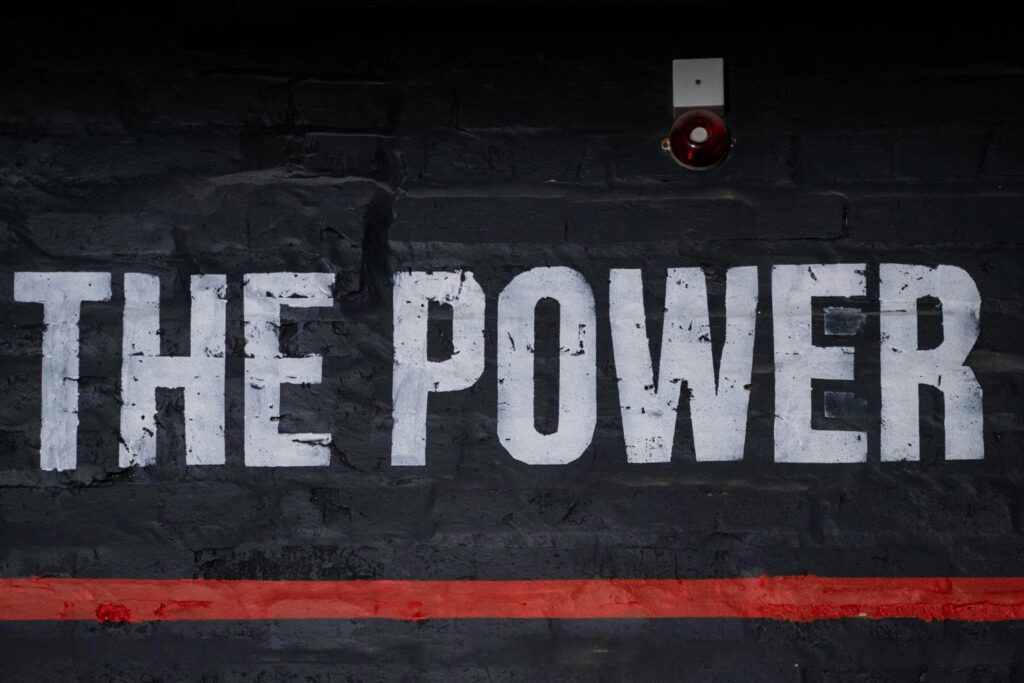 Close-up of 'The Power' graffiti on a dark wall, emphasizing strength and impact.